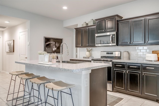 16556 White Fish Ln, Justin, TX 76247 - kitchen with stainless steel appliances, a sink, light tile patterned floors, a kitchen breakfast bar, and tasteful backsplash