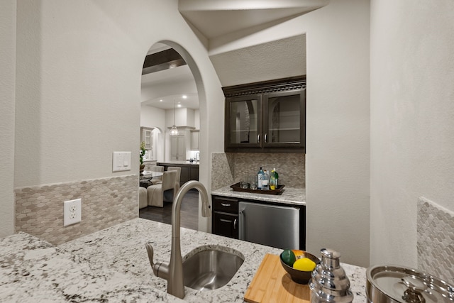 2100 Veranda Ave, Trophy Club, TX 76262 - kitchen featuring a sink, light stone counters, arched walkways, stainless steel dishwasher, and tasteful backsplash