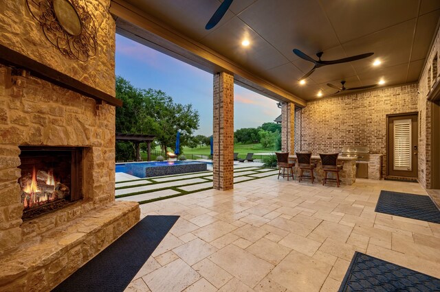 2100 Veranda Ave, Trophy Club, TX 76262 - patio terrace at dusk with an outdoor stone fireplace, ceiling fan, an outdoor pool, a patio, and exterior bar