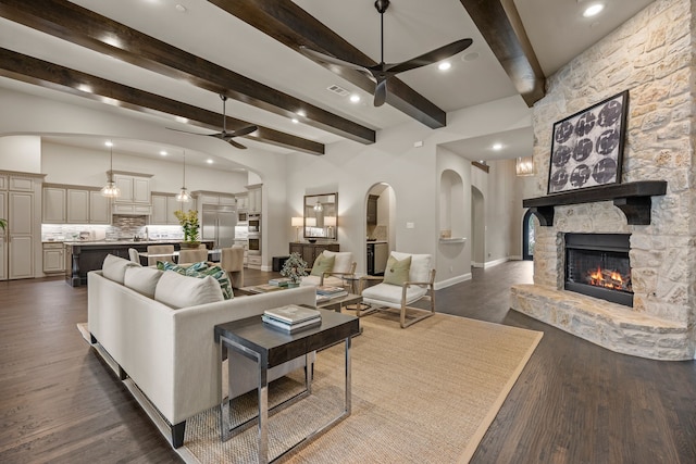 2100 Veranda Ave, Trophy Club, TX 76262 - living room with a ceiling fan, arched walkways, a fireplace, beamed ceiling, and dark wood finished floors