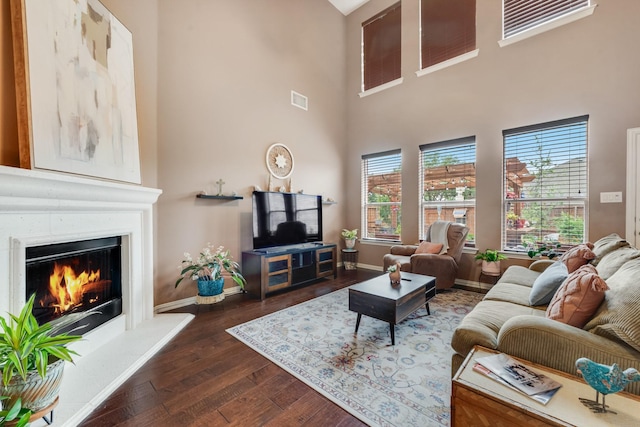 1090 Potter Ave, Rockwall, TX 75087 - living area featuring dark wood-type flooring, a lit fireplace, a towering ceiling, and baseboards