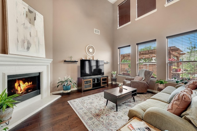 1090 Potter Ave, Rockwall, TX 75087 - living room featuring dark wood-style flooring, a lit fireplace, baseboards, and a high ceiling