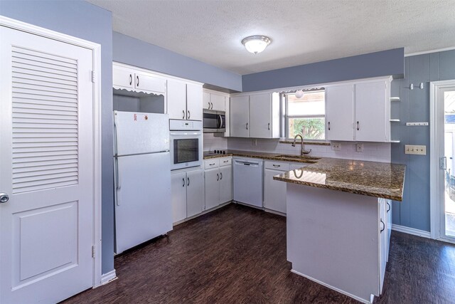8351-8353 Lullwater Dr, Dallas, TX 75218 - kitchen featuring white appliances, a sink, a peninsula, dark wood-style flooring, and a textured ceiling