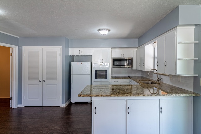 8351-8353 Lullwater Dr, Dallas, TX 75218 - kitchen featuring white appliances, a sink, open shelves, a peninsula, and dark wood-type flooring