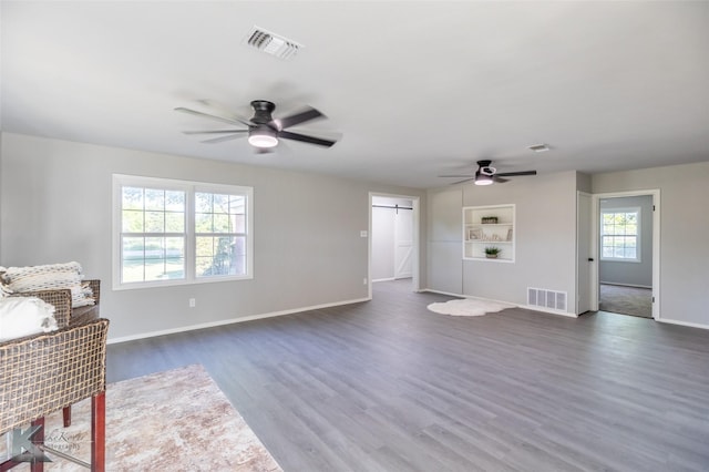 821 Cherry Ln, Clyde, TX 79510 - unfurnished living room featuring a barn door, a ceiling fan, dark wood-type flooring, baseboards, and built in features