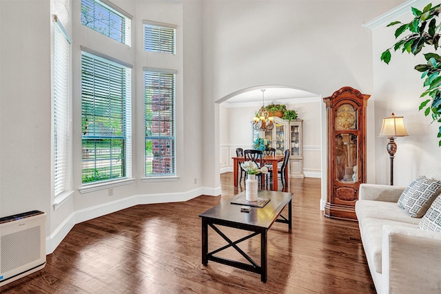 1217 Kent Brown Rd, Garland, TX 75044 - living room with a high ceiling, arched walkways, wood finished floors, a chandelier, and baseboards
