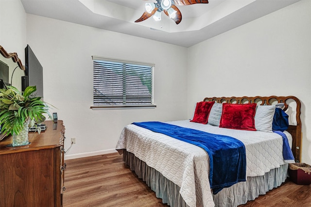 1217 Kent Brown Rd, Garland, TX 75044 - bedroom featuring wood finished floors, baseboards, ceiling fan, and a raised ceiling