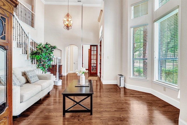 1217 Kent Brown Rd, Garland, TX 75044 - living room with arched walkways, a chandelier, dark wood-style flooring, baseboards, and ornamental molding