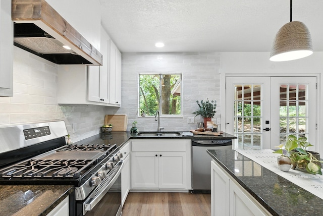 1423 W Ball St, Weatherford, TX 76086 - kitchen with appliances with stainless steel finishes, range hood, plenty of natural light, white cabinetry, and a textured ceiling