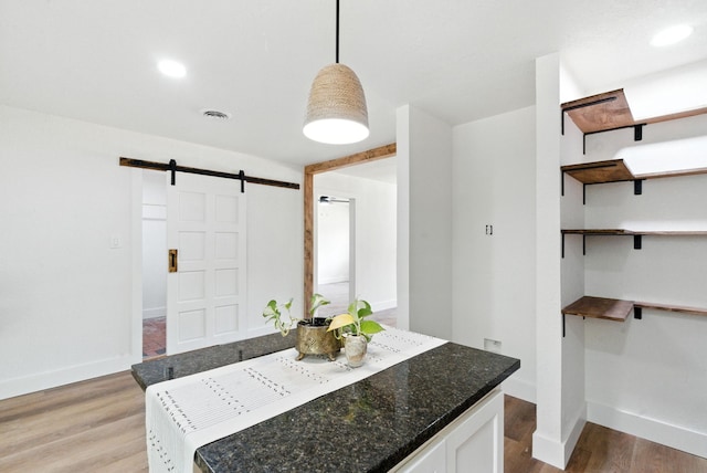 1423 W Ball St, Weatherford, TX 76086 - kitchen featuring a barn door, light wood-style flooring, open shelves, white cabinets, and decorative light fixtures