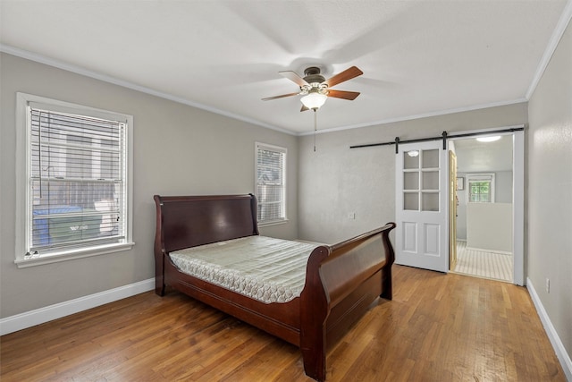 2530 Colcord, Waco, TX 76707 - bedroom featuring a barn door, ornamental molding, wood finished floors, baseboards, and a ceiling fan