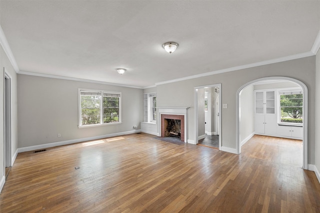 2530 Colcord, Waco, TX 76707 - unfurnished living room featuring built in features, hardwood / wood-style flooring, ornamental molding, baseboards, and arched walkways