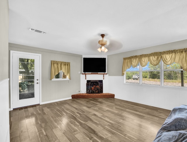323 W Rentz St, Weatherford, TX 76086 - unfurnished living room with wood finished floors, a ceiling fan, a warm lit fireplace, and baseboards