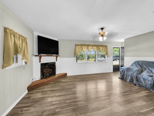 323 W Rentz St, Weatherford, TX 76086 - unfurnished living room with wood finished floors, a brick fireplace, a wainscoted wall, and a ceiling fan