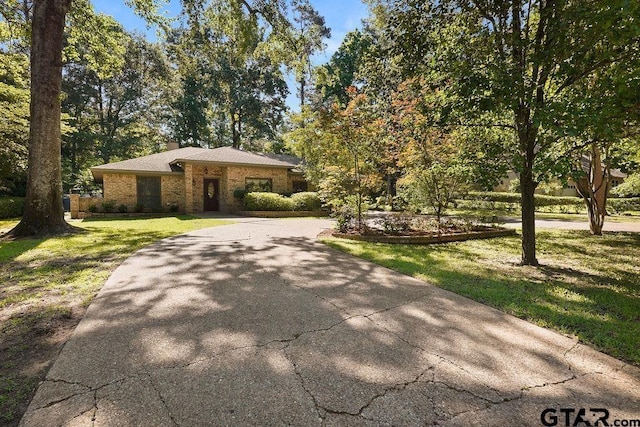 641 Hideaway Ln E, Hideaway, TX 75771 - view of front facade featuring curved driveway, a front yard, brick siding, and a chimney
