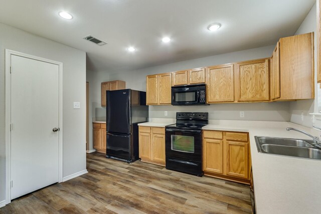 1508 Caymus Ct, Lewisville, TX 75067 - kitchen with black appliances, a sink, wood finished floors, light countertops, and recessed lighting