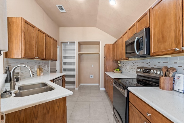 10328 Lone Pine Ln, Fort Worth, TX 76108 - kitchen with stainless steel appliances, a sink, vaulted ceiling, light countertops, and brown cabinets