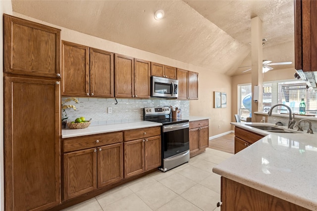 10328 Lone Pine Ln, Fort Worth, TX 76108 - kitchen featuring appliances with stainless steel finishes, a sink, lofted ceiling, tasteful backsplash, and brown cabinets