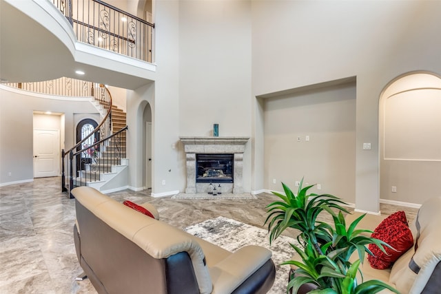 7209 Joshua Tree Trl, Mckinney, TX 75070 - living area with arched walkways, a towering ceiling, stairs, a premium fireplace, and baseboards