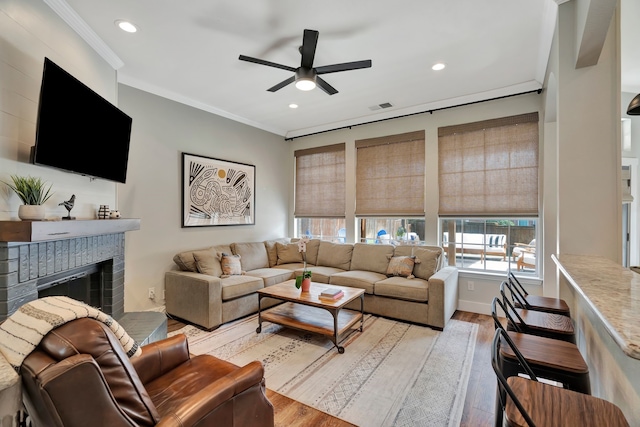 940 Crown Ct, Highland Village, TX 75077 - living room featuring ceiling fan, a brick fireplace, light wood-style floors, ornamental molding, and recessed lighting