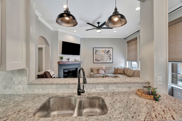 940 Crown Ct, Highland Village, TX 75077 - kitchen with a sink, a brick fireplace, ornamental molding, ceiling fan, and tasteful backsplash