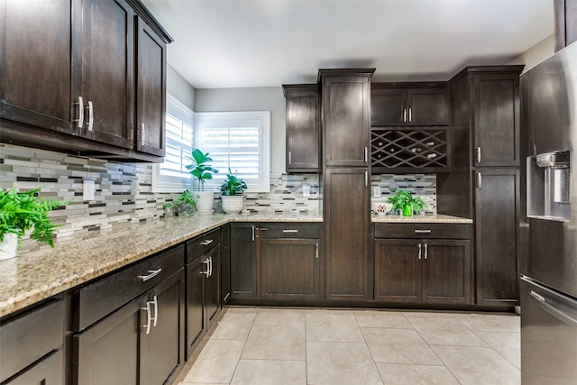 1117 Brandy Sta, Richardson, TX 75080 - kitchen with stainless steel fridge, light tile patterned flooring, decorative backsplash, dark brown cabinetry, and light stone counters