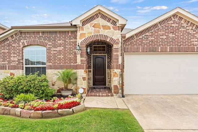 8400 Sioux Trl, Aubrey, TX 76227 - property entrance with brick siding, stone siding, a garage, and driveway