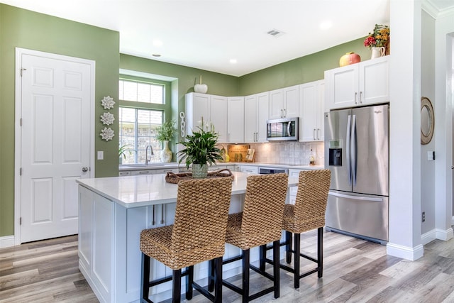 10108 Hunter Run, Frisco, TX 75035 - kitchen featuring stainless steel appliances, light countertops, white cabinetry, light wood-type flooring, and recessed lighting