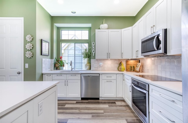 10108 Hunter Run, Frisco, TX 75035 - kitchen with stainless steel appliances, white cabinets, light wood-type flooring, light countertops, and decorative backsplash