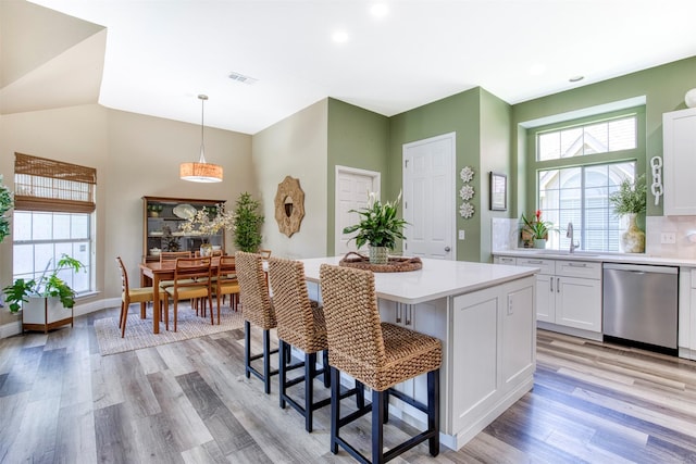 10108 Hunter Run, Frisco, TX 75035 - kitchen featuring stainless steel dishwasher, a kitchen breakfast bar, light wood-type flooring, light countertops, and recessed lighting