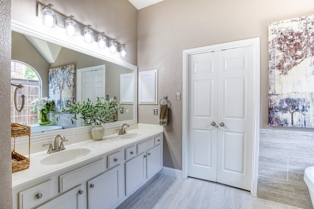 10108 Hunter Run, Frisco, TX 75035 - bathroom with double vanity, a freestanding tub, and vaulted ceiling