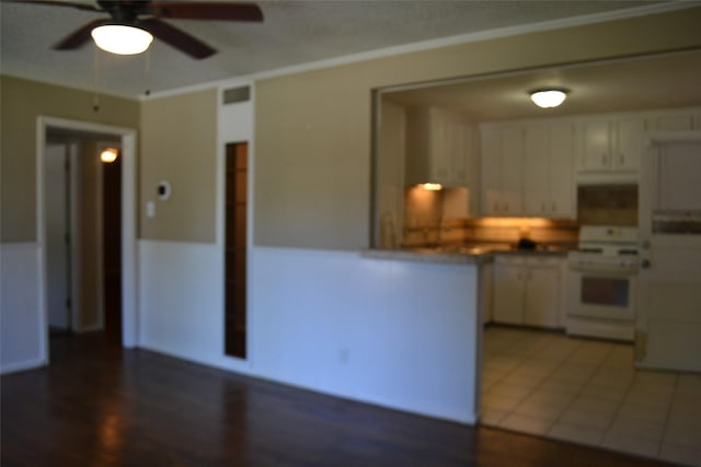 202 Pine St, Arlington, TX 76011 - kitchen featuring electric range, ceiling fan, white cabinetry, a peninsula, and wood finished floors