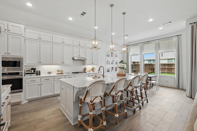 1809 Lithgow Rd, Celina, TX 75009 - kitchen featuring stainless steel appliances, a sink, white cabinetry, a center island with sink, and a kitchen bar