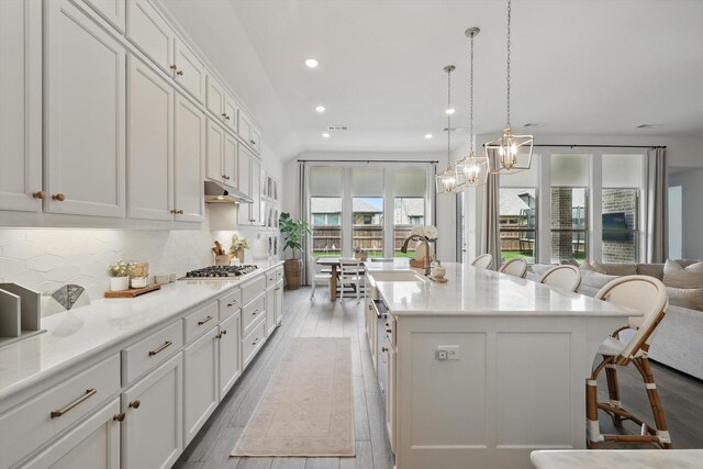1809 Lithgow Rd, Celina, TX 75009 - kitchen featuring a kitchen breakfast bar, a sink, tasteful backsplash, under cabinet range hood, and white cabinetry