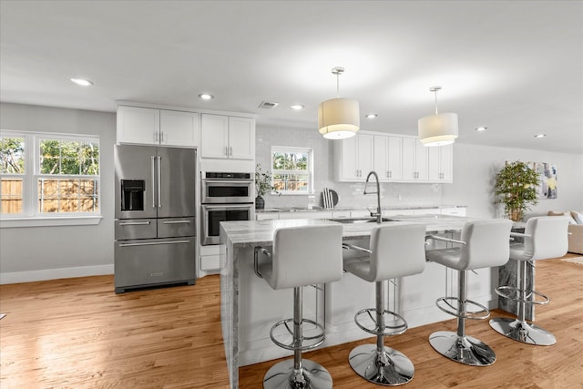 1705 Provincetown Ln, Richardson, TX 75080 - kitchen featuring appliances with stainless steel finishes, light wood finished floors, a sink, white cabinets, and recessed lighting