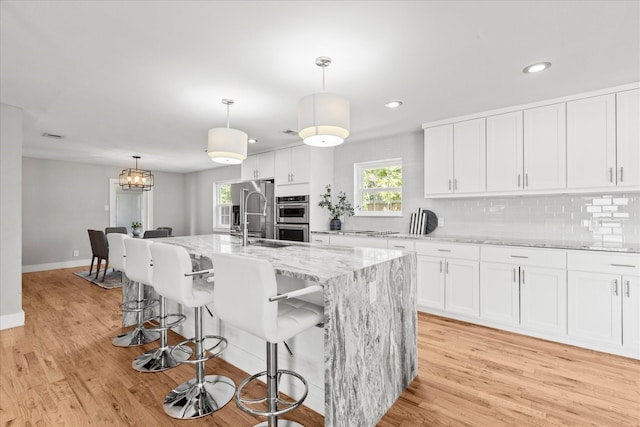 1705 Provincetown Ln, Richardson, TX 75080 - kitchen with stainless steel double oven, light wood-style flooring, white cabinetry, light stone countertops, and recessed lighting