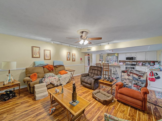 1824 Castille Dr, Carrollton, TX 75007 - living room with track lighting, light wood finished floors, a ceiling fan, and a textured ceiling
