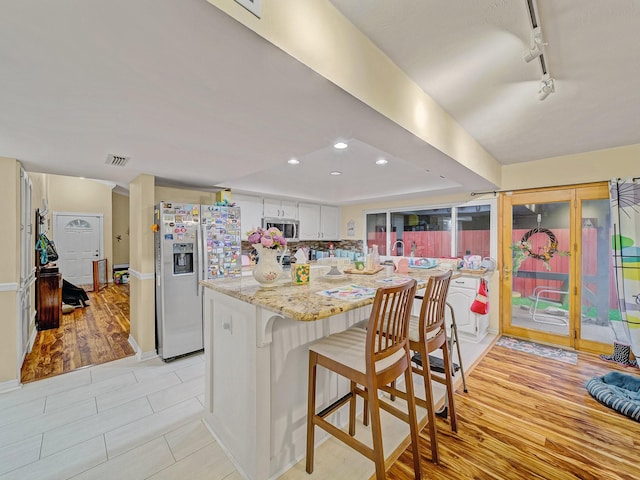 1824 Castille Dr, Carrollton, TX 75007 - kitchen featuring appliances with stainless steel finishes, a breakfast bar, track lighting, recessed lighting, and light stone counters