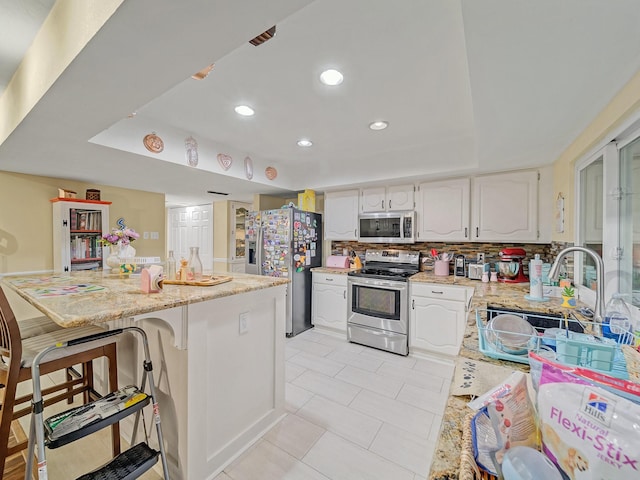 1824 Castille Dr, Carrollton, TX 75007 - kitchen featuring appliances with stainless steel finishes, a sink, a tray ceiling, white cabinets, and recessed lighting