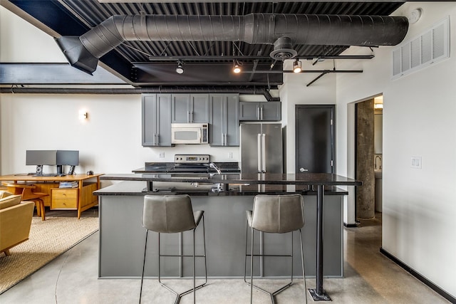 3110 Thomas Ave Unit 535, Dallas, TX 75204 - kitchen featuring appliances with stainless steel finishes, finished concrete floors, dark countertops, a breakfast bar, and a kitchen island with sink