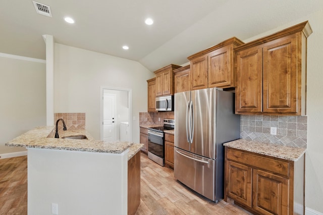 2304 Forest Hill Ln, Granbury, TX 76048 - kitchen with stainless steel appliances, a sink, a peninsula, backsplash, and light wood finished floors