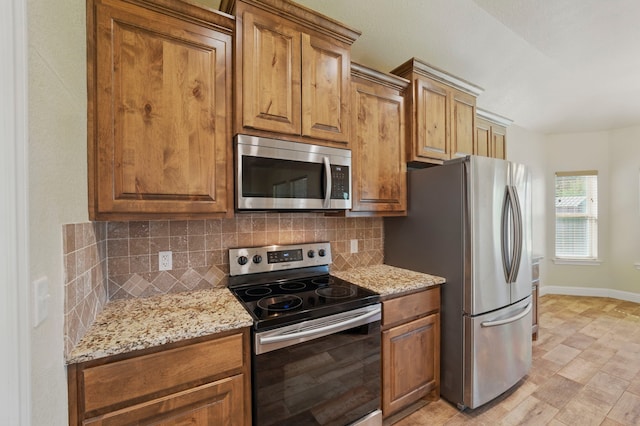 2304 Forest Hill Ln, Granbury, TX 76048 - kitchen with appliances with stainless steel finishes, tasteful backsplash, light stone counters, brown cabinets, and baseboards