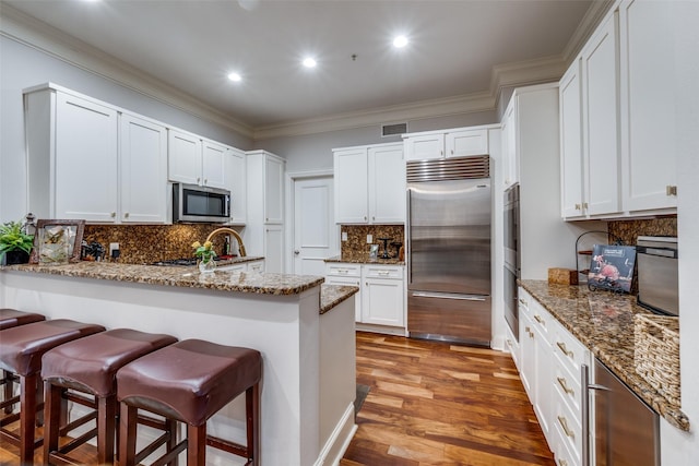 3303 Blackburn St Unit 402, Dallas, TX 75204 - kitchen with appliances with stainless steel finishes, a peninsula, a breakfast bar, decorative backsplash, and stone countertops