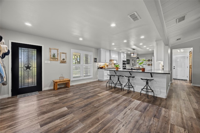 3280 Shady Grove Rd, Midlothian, TX 76065 - kitchen featuring dark countertops, dark wood-type flooring, white cabinetry, a breakfast bar area, and recessed lighting