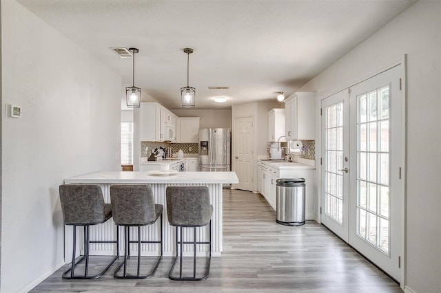 1308 Stetson Trl, Saginaw, TX 76131 - kitchen featuring a peninsula, stainless steel fridge, decorative backsplash, and white cabinets