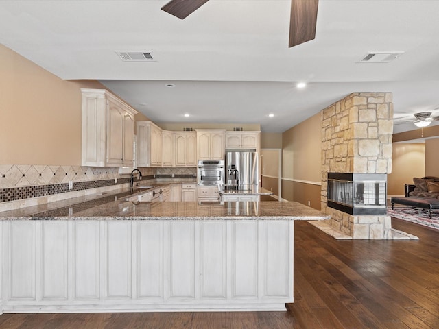 333 Forest Trl, Weatherford, TX 76085 - kitchen featuring appliances with stainless steel finishes, stone countertops, a peninsula, and decorative backsplash