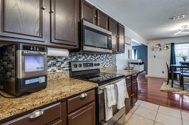 7419 Concordia Ln, Dallas, TX 75241 - kitchen with appliances with stainless steel finishes, backsplash, dark brown cabinets, light tile patterned floors, and a textured ceiling
