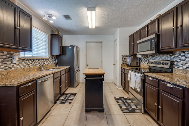 7419 Concordia Ln, Dallas, TX 75241 - kitchen featuring stainless steel appliances, a textured ceiling, backsplash, dark brown cabinetry, and a sink