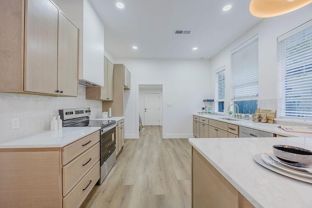 1410 Lee Ave, Fort Worth, TX 76164 - kitchen featuring stainless steel electric range oven, a sink, light wood finished floors, light countertops, and decorative backsplash