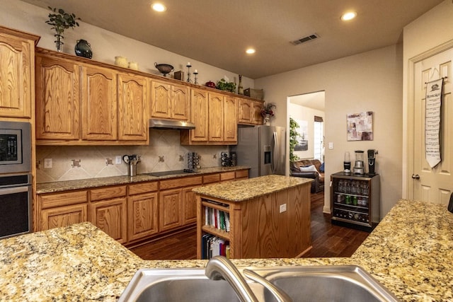 2324 Stone Creek Dr, Mckinney, TX 75072 - kitchen with appliances with stainless steel finishes, under cabinet range hood, dark wood-type flooring, a center island, and tasteful backsplash